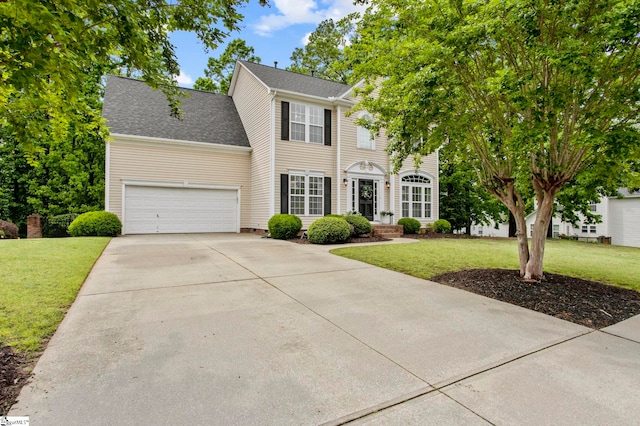 colonial-style house with a garage, driveway, and a front yard