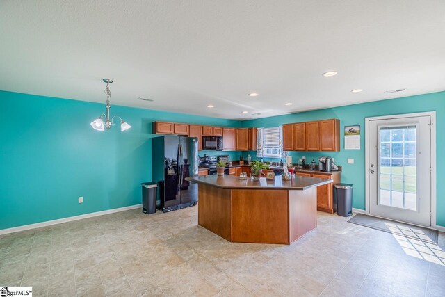 kitchen featuring brown cabinets, dark countertops, an inviting chandelier, a kitchen island, and black appliances