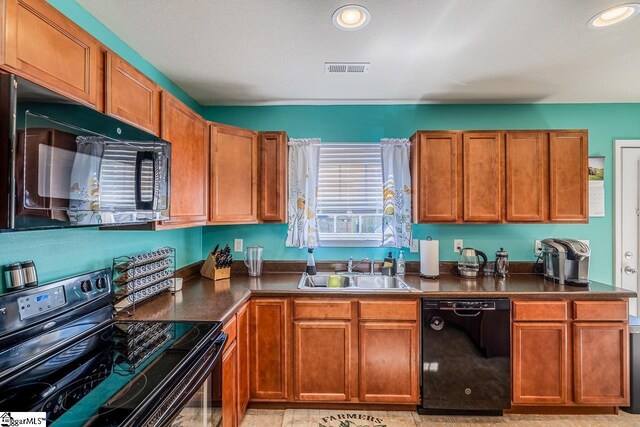 kitchen featuring brown cabinetry, visible vents, dark countertops, a sink, and black appliances