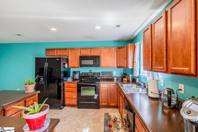 kitchen with brown cabinets, dark countertops, a sink, visible vents, and black appliances