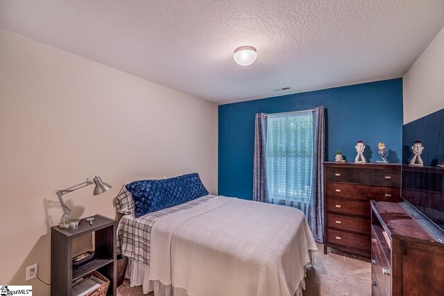 bedroom with carpet floors, a textured ceiling, and visible vents