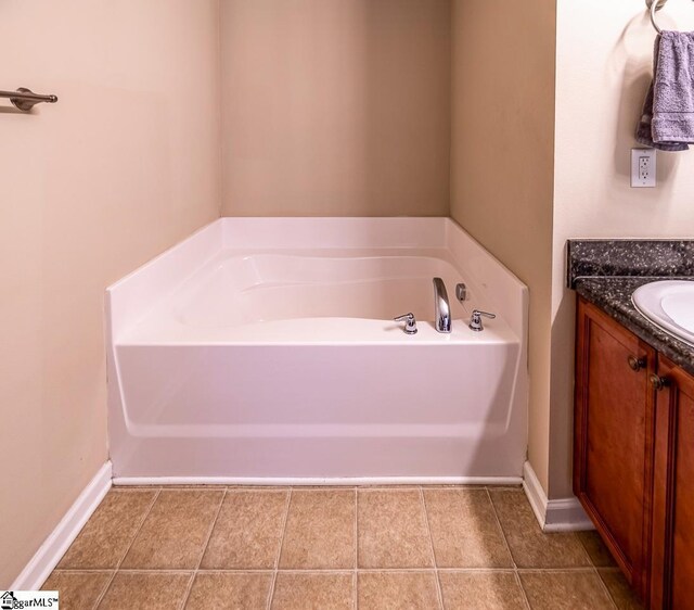 full bath featuring vanity, tile patterned flooring, baseboards, and a garden tub