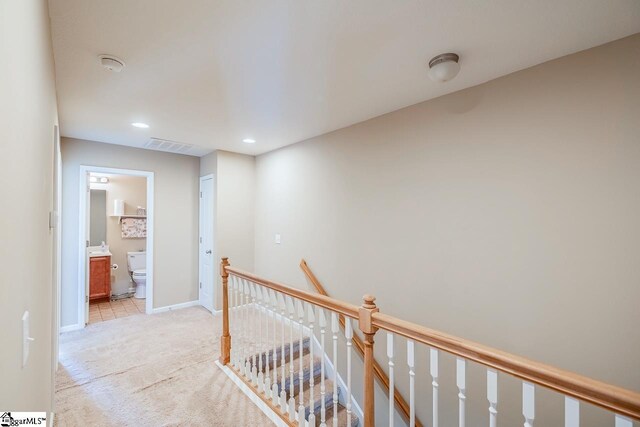 hallway featuring visible vents, baseboards, light colored carpet, recessed lighting, and an upstairs landing