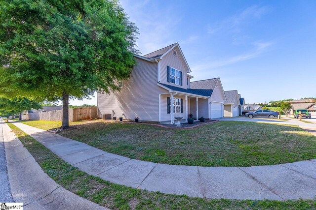 traditional-style home featuring a garage, fence, driveway, and a front lawn