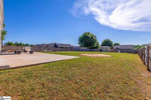 view of yard with a patio, a fenced backyard, a shed, and an outbuilding