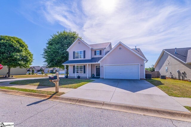 traditional-style house with fence, a garage, a front yard, central air condition unit, and driveway