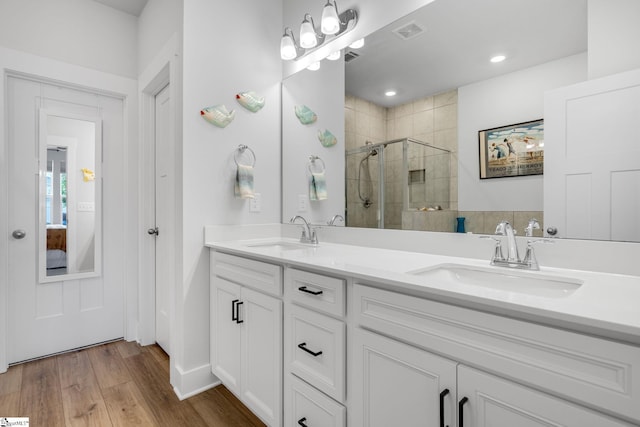 full bathroom with wood finished floors, visible vents, a sink, and a stall shower