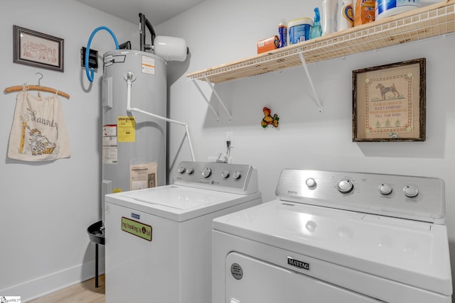 clothes washing area with laundry area, light wood finished floors, baseboards, washer and clothes dryer, and electric water heater