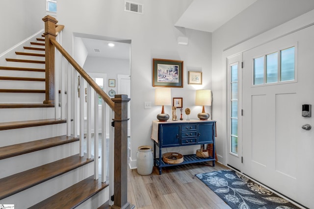 foyer entrance with visible vents, wood finished floors, and stairway