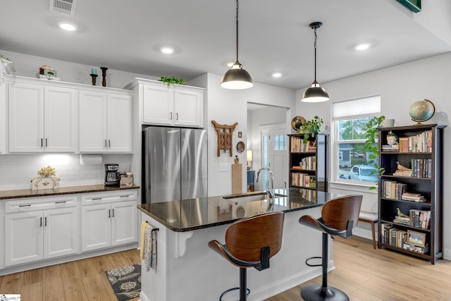 kitchen featuring a sink, white cabinets, freestanding refrigerator, and visible vents