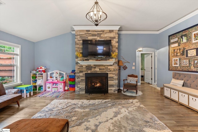 living area featuring arched walkways, a fireplace, wood finished floors, and a chandelier