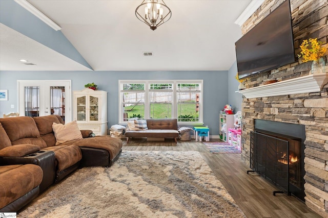 living area with a stone fireplace, visible vents, vaulted ceiling, wood finished floors, and baseboards