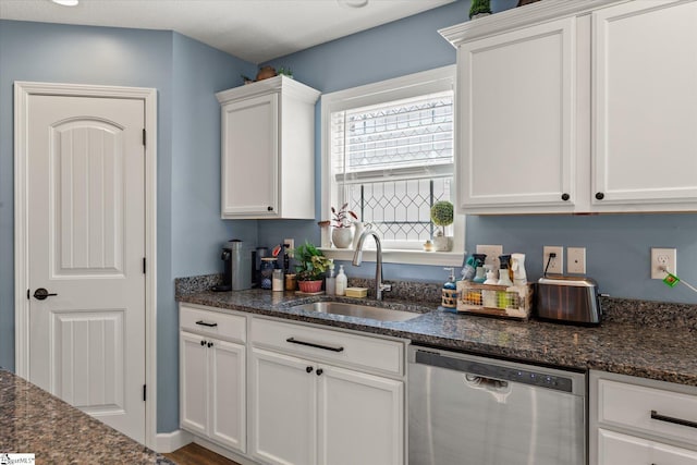 kitchen featuring a sink, dark stone counters, stainless steel dishwasher, and white cabinetry