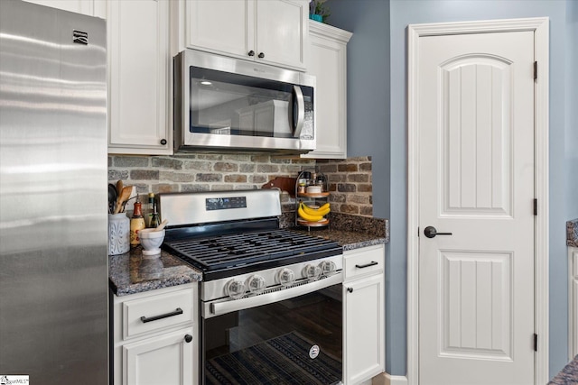kitchen with white cabinets, stainless steel appliances, decorative backsplash, and dark stone countertops