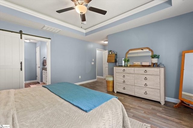 bedroom with visible vents, crown molding, wood finished floors, a barn door, and a raised ceiling