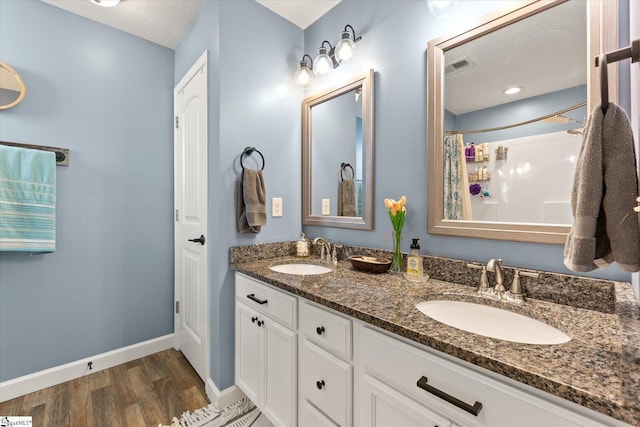 full bath with a sink, baseboards, wood finished floors, and visible vents