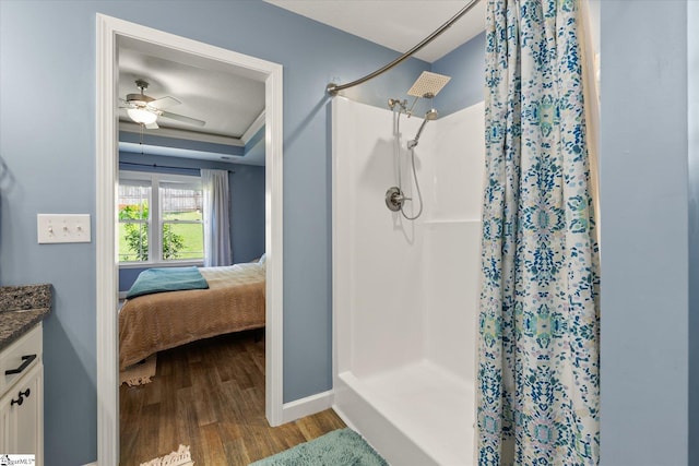 bathroom with vanity, a ceiling fan, baseboards, a shower stall, and wood finished floors