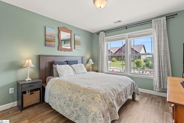bedroom featuring baseboards, wood finished floors, and visible vents