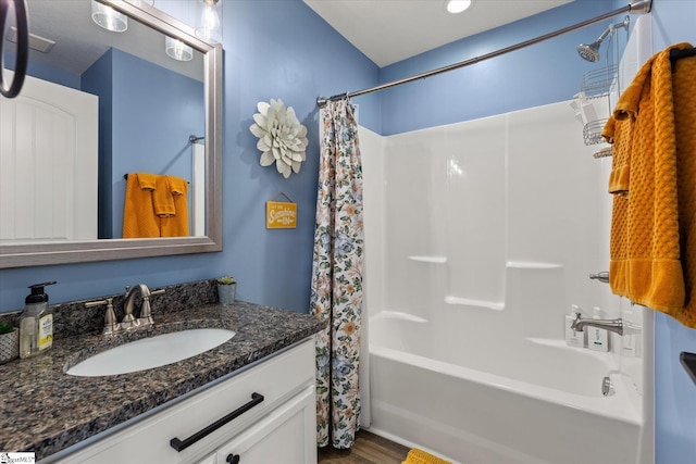 full bath featuring vanity, wood finished floors, and shower / tub combo