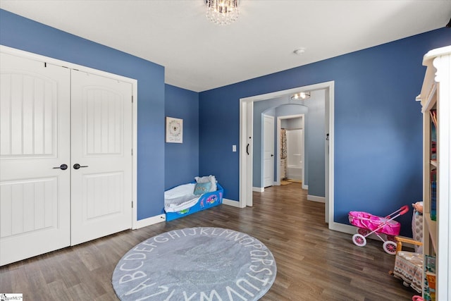 interior space featuring baseboards, arched walkways, wood finished floors, and a closet