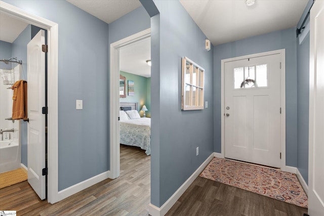 entryway with baseboards, arched walkways, and wood finished floors
