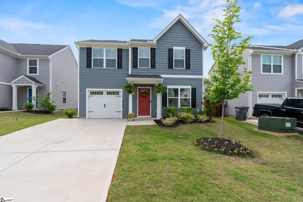 traditional-style home featuring a garage, concrete driveway, and a front lawn