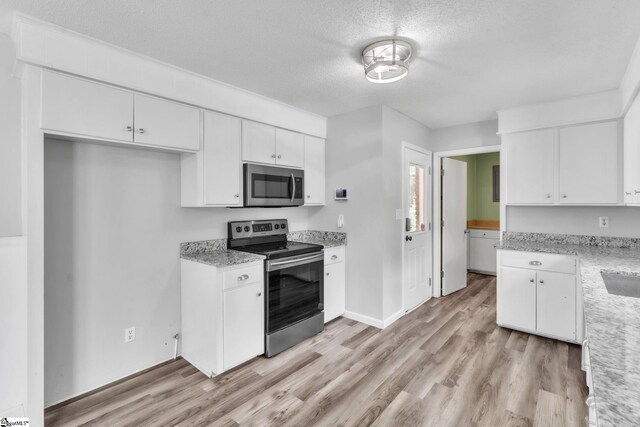 kitchen featuring white cabinetry, a textured ceiling, appliances with stainless steel finishes, and light wood-style flooring