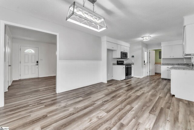 unfurnished living room with a sink, baseboards, and light wood-style flooring