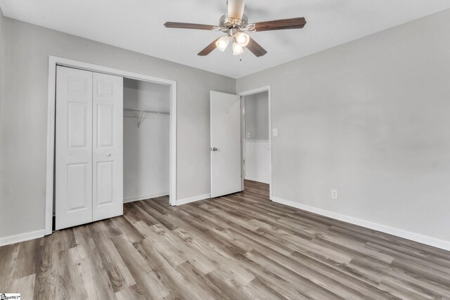 unfurnished bedroom featuring baseboards, a ceiling fan, wood finished floors, and a closet