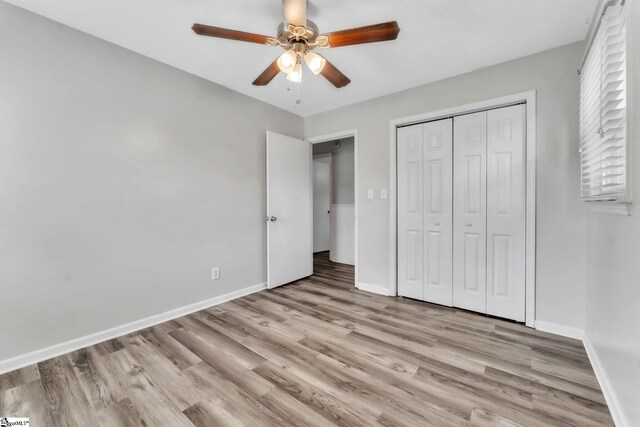 unfurnished bedroom featuring light wood-style floors, baseboards, a ceiling fan, and a closet