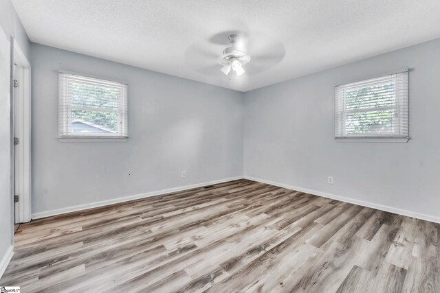 empty room with baseboards, a textured ceiling, ceiling fan, and wood finished floors
