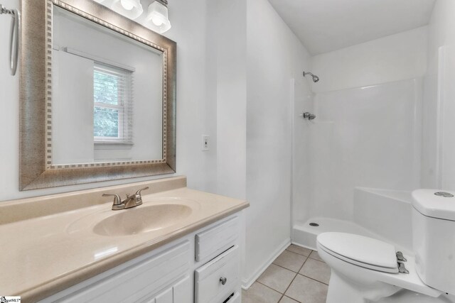 bathroom featuring vanity, tile patterned flooring, toilet, and a shower