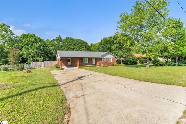 single story home with fence, brick siding, a front yard, a carport, and driveway