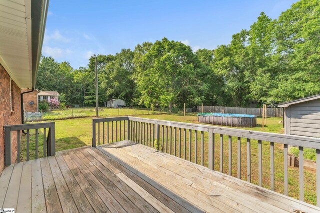 wooden terrace with a lawn, a fenced in pool, a storage shed, and a fenced backyard