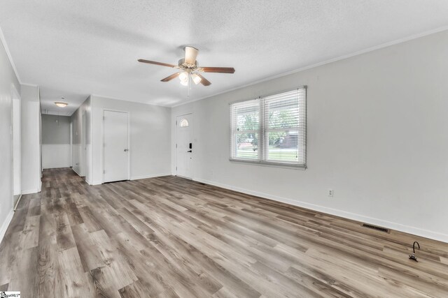 unfurnished living room featuring ornamental molding, wood finished floors, baseboards, ceiling fan, and a textured ceiling