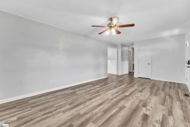 unfurnished room featuring a ceiling fan, visible vents, crown molding, wood finished floors, and baseboards