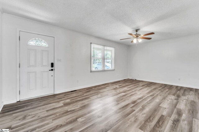 entrance foyer featuring a textured ceiling, baseboards, a ceiling fan, and wood finished floors