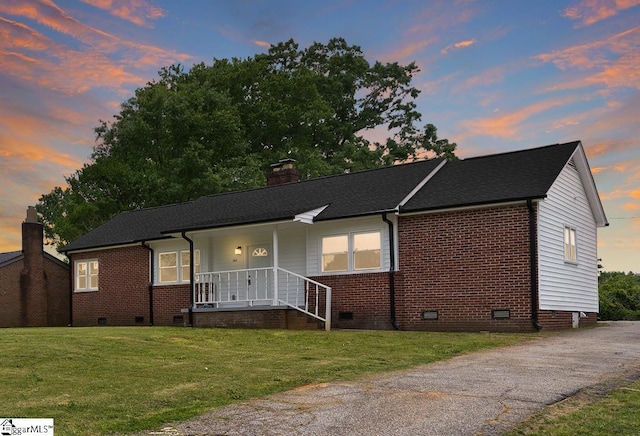 view of front of home with a chimney, a lawn, and crawl space