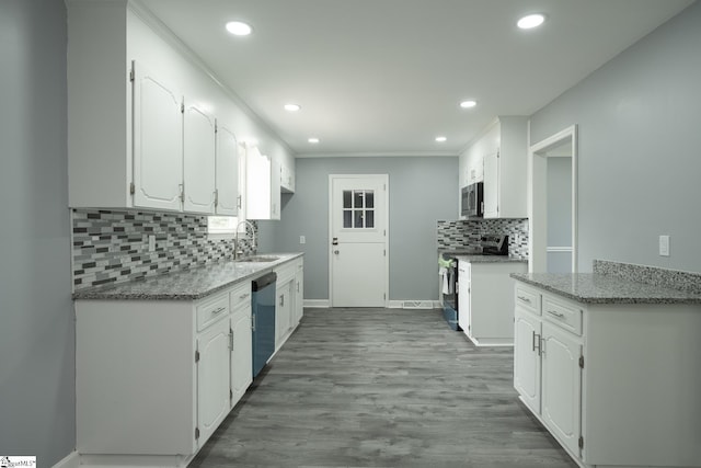 kitchen with a sink, stainless steel appliances, recessed lighting, white cabinetry, and tasteful backsplash