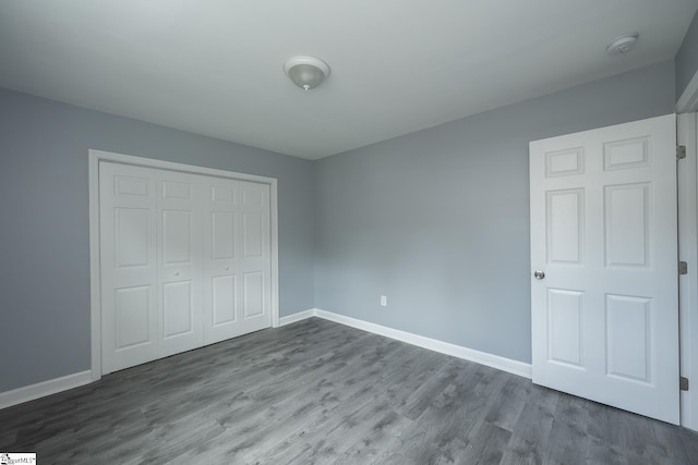 unfurnished bedroom with a closet, baseboards, and wood finished floors