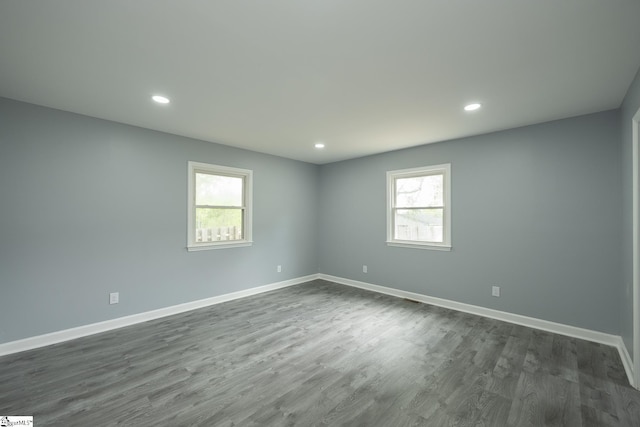 empty room with baseboards, dark wood-style flooring, and a wealth of natural light