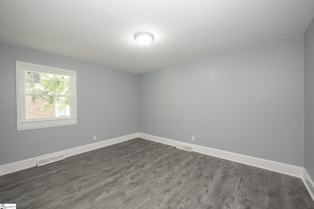 spare room with visible vents, baseboards, and dark wood-type flooring