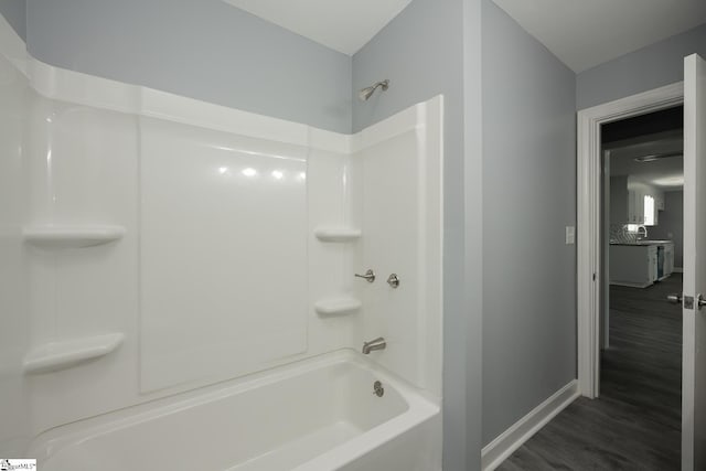 full bathroom featuring a sink, baseboards, bathing tub / shower combination, and wood finished floors