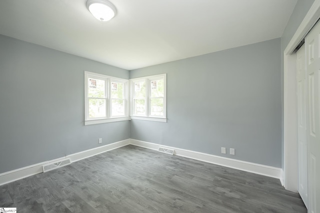 unfurnished bedroom featuring visible vents, baseboards, and dark wood-style flooring