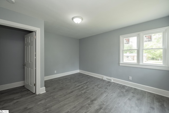 unfurnished bedroom featuring baseboards, dark wood-style floors, and visible vents