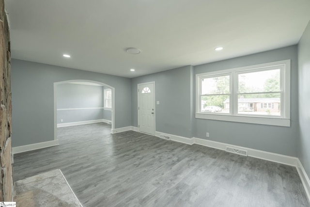 interior space featuring visible vents, wood finished floors, baseboards, recessed lighting, and arched walkways