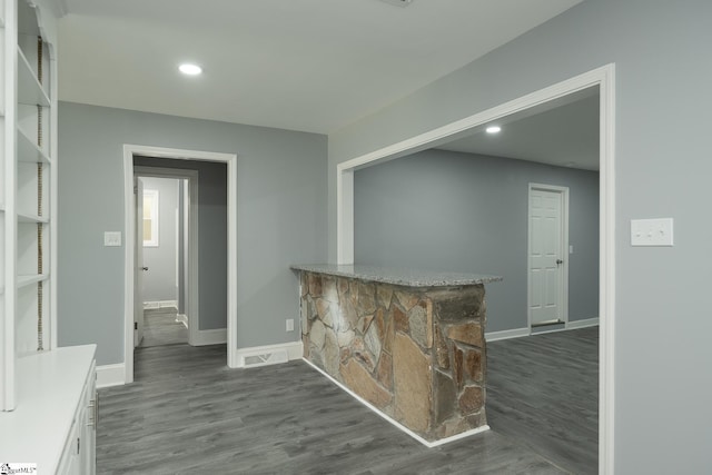 bar with a bar, dark wood-style flooring, and baseboards
