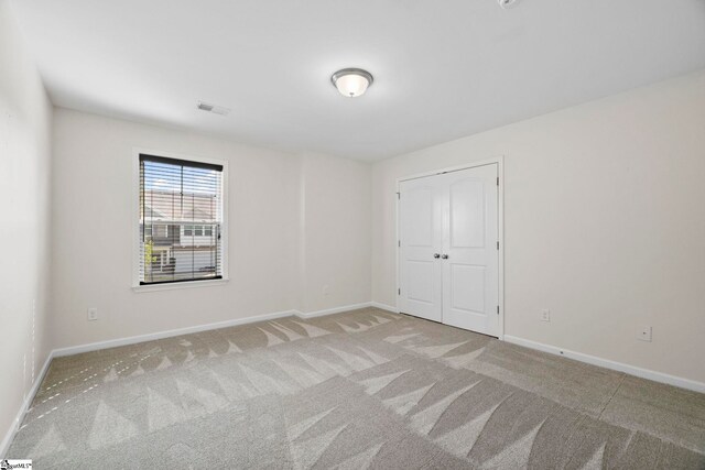 unfurnished room with baseboards, visible vents, and light carpet
