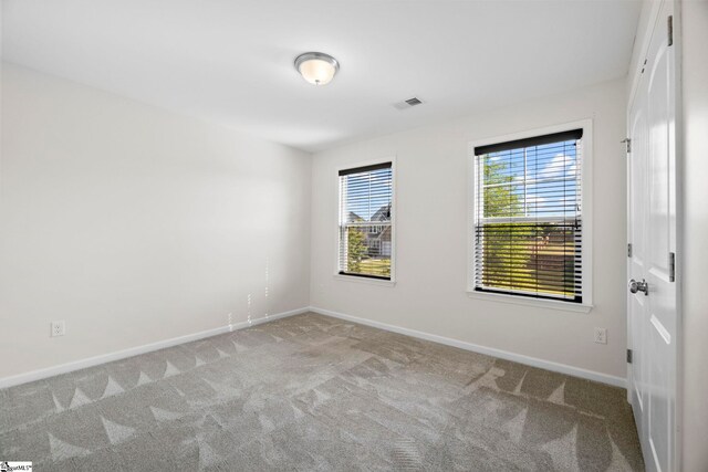 carpeted empty room featuring baseboards and visible vents