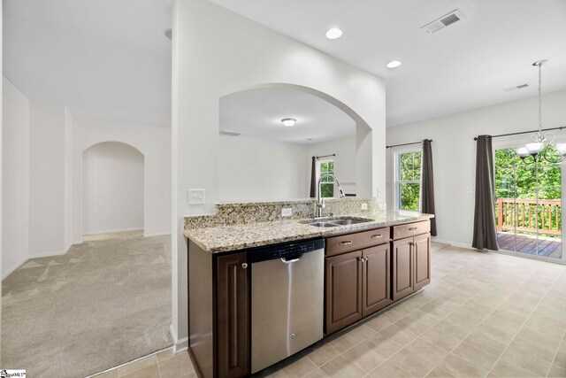 kitchen with light stone countertops, a sink, arched walkways, stainless steel dishwasher, and visible vents